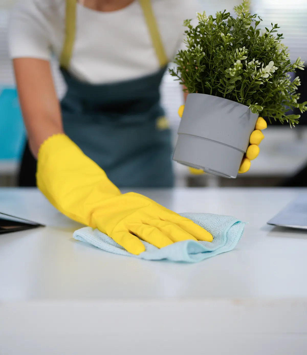 Junge Frau in gelben Handschuhen putzt den Tisch im Büro. - Büroreinigng - Hannover